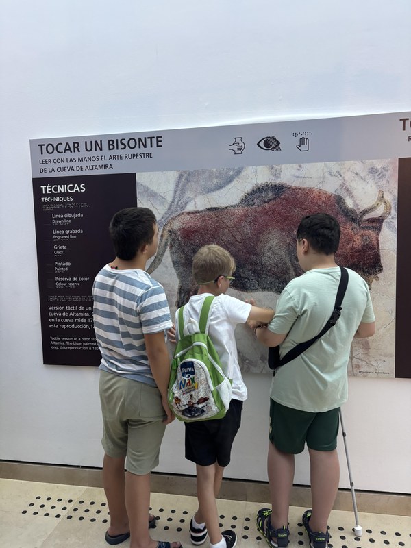 Tres participantes visitando el museo de Altamira, tocando sus relieves