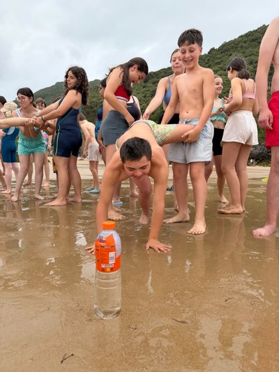 Participantes tratando de alejar la botella sin usar las manos durante la gymkana en la playa