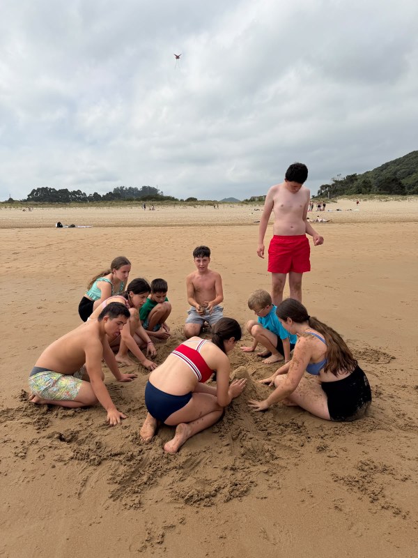 Grupo de participantes construyendo un castillo en la arena de la playa