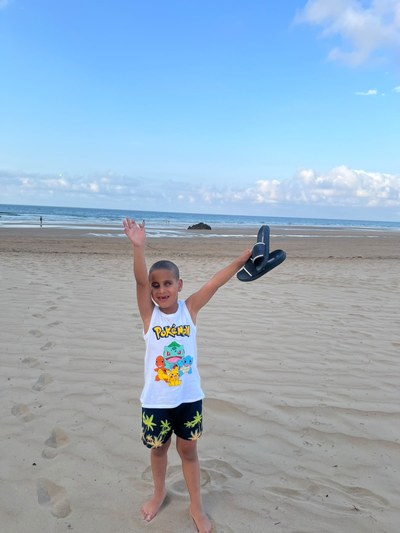 Participante, en la playa con los brazos en alto