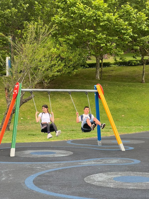 Dos participantes se balancean en los columpios de un parque