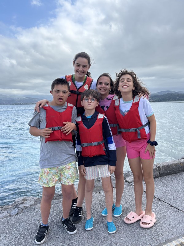 Campistas preparados para subir al barco de vela con chalecos rojos