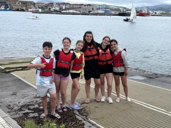 Campistas preparados para subir al barco de vela con chalecos rojos