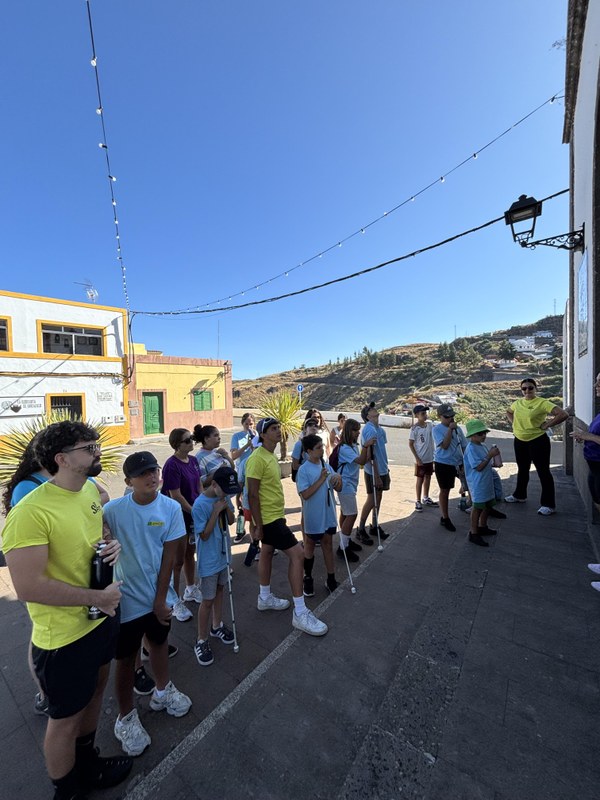 Grupo de participantes de pie frente a la parroquia,  escuchando las explicaciones del guía.