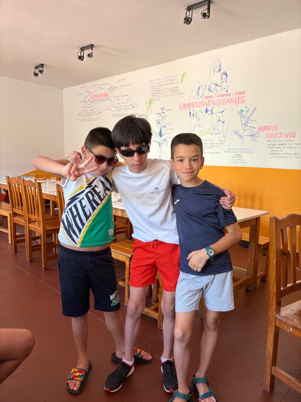 Tres participantes agarrados saludando a la cámara.