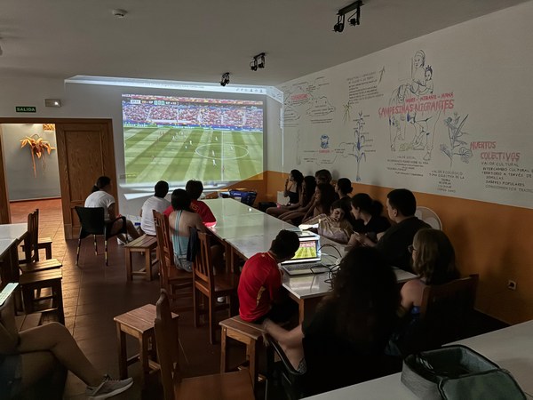 Participantes viendo el partido de España proyectado en la pared