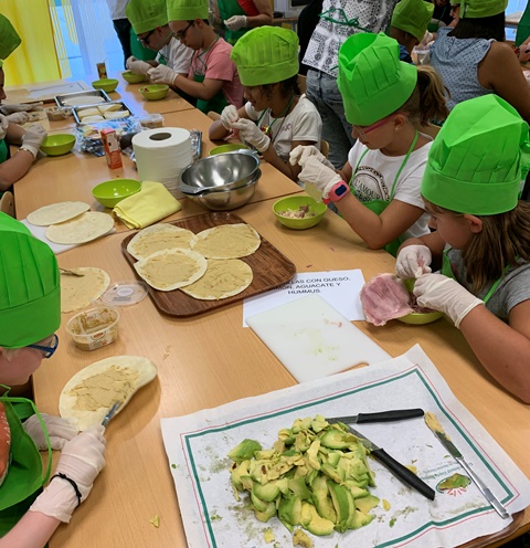 Los partipantes elaborando quesadillas con hummus y con aguacate