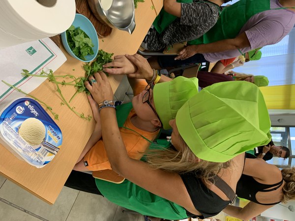 Uno de los participantes, acompañado de la mediadora, realiza la receta de fresas con helado de vainilla y aguacate