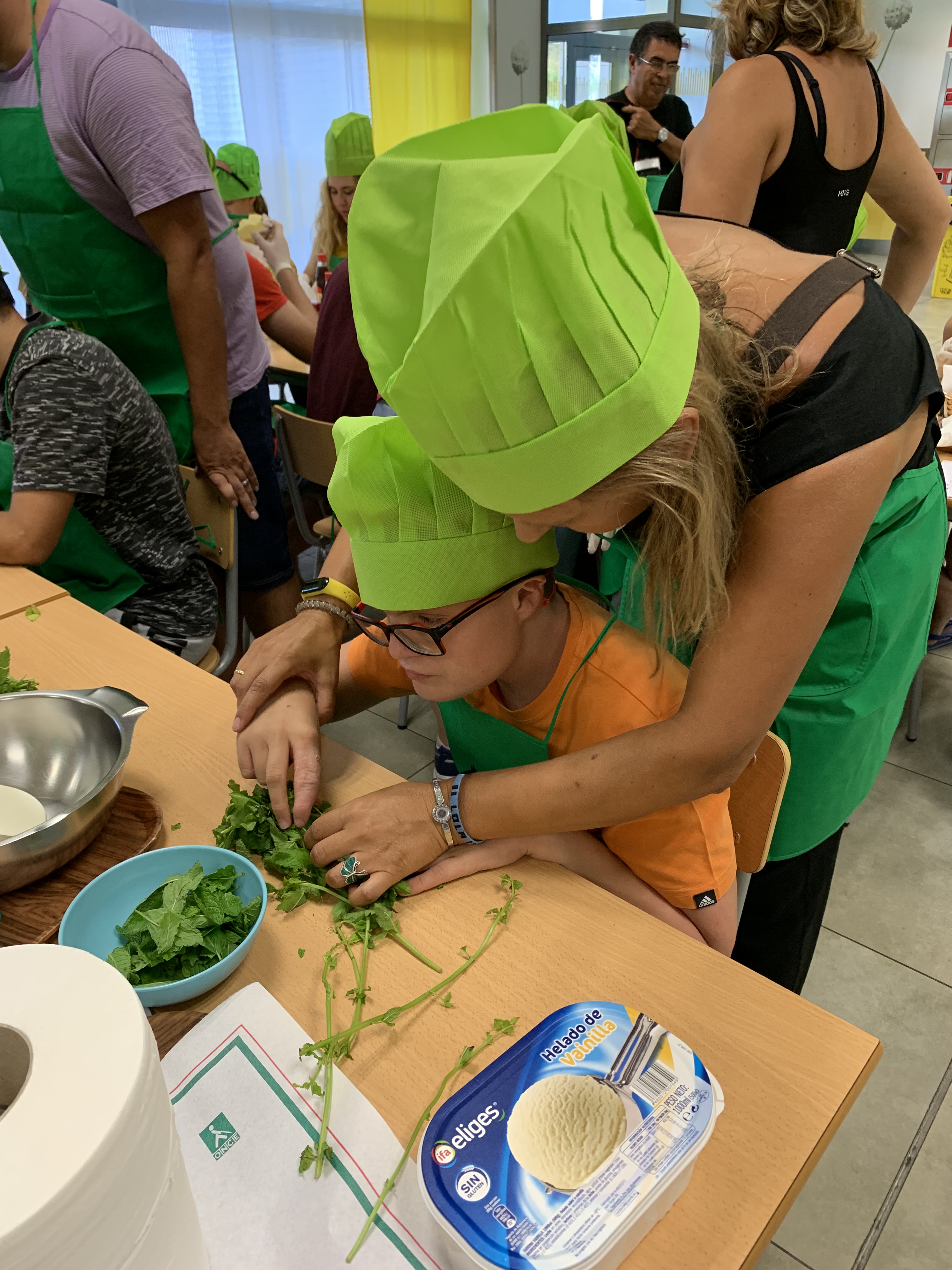 Uno de los participantes, acompañado de la mediadora, realiza la receta de fresas con helado de vainilla y aguacate